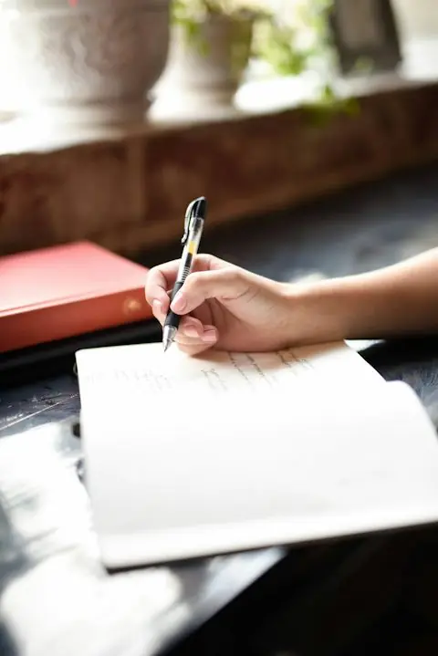 Estudiante escribiendo su tesis a mano en un cuaderno